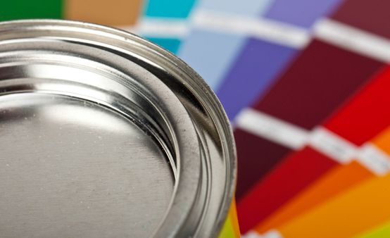Lata de pintura con paletas de colores al fondo