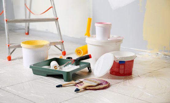 Potes de pintura con rodillos y brochas para pintar pared